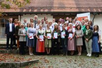 Personengruppe mit Urkunden vor einem Gebäude